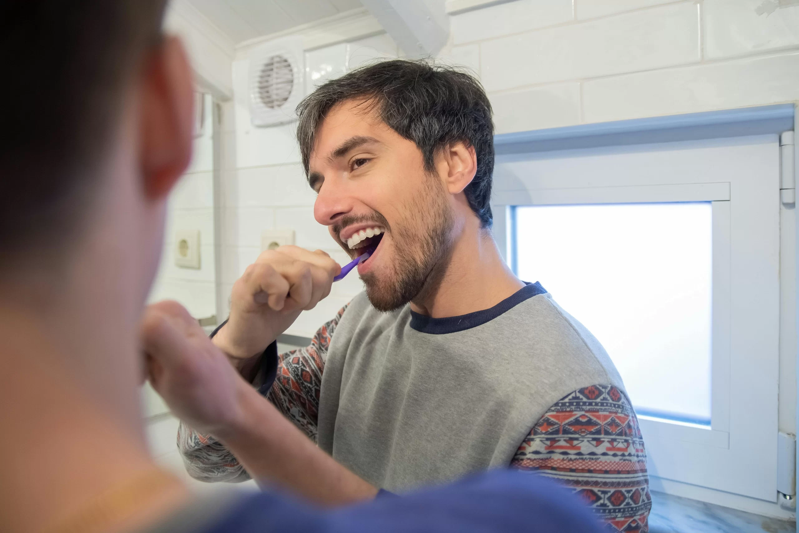 Man enjoying brushing his teeth knowing he has fresh breath.