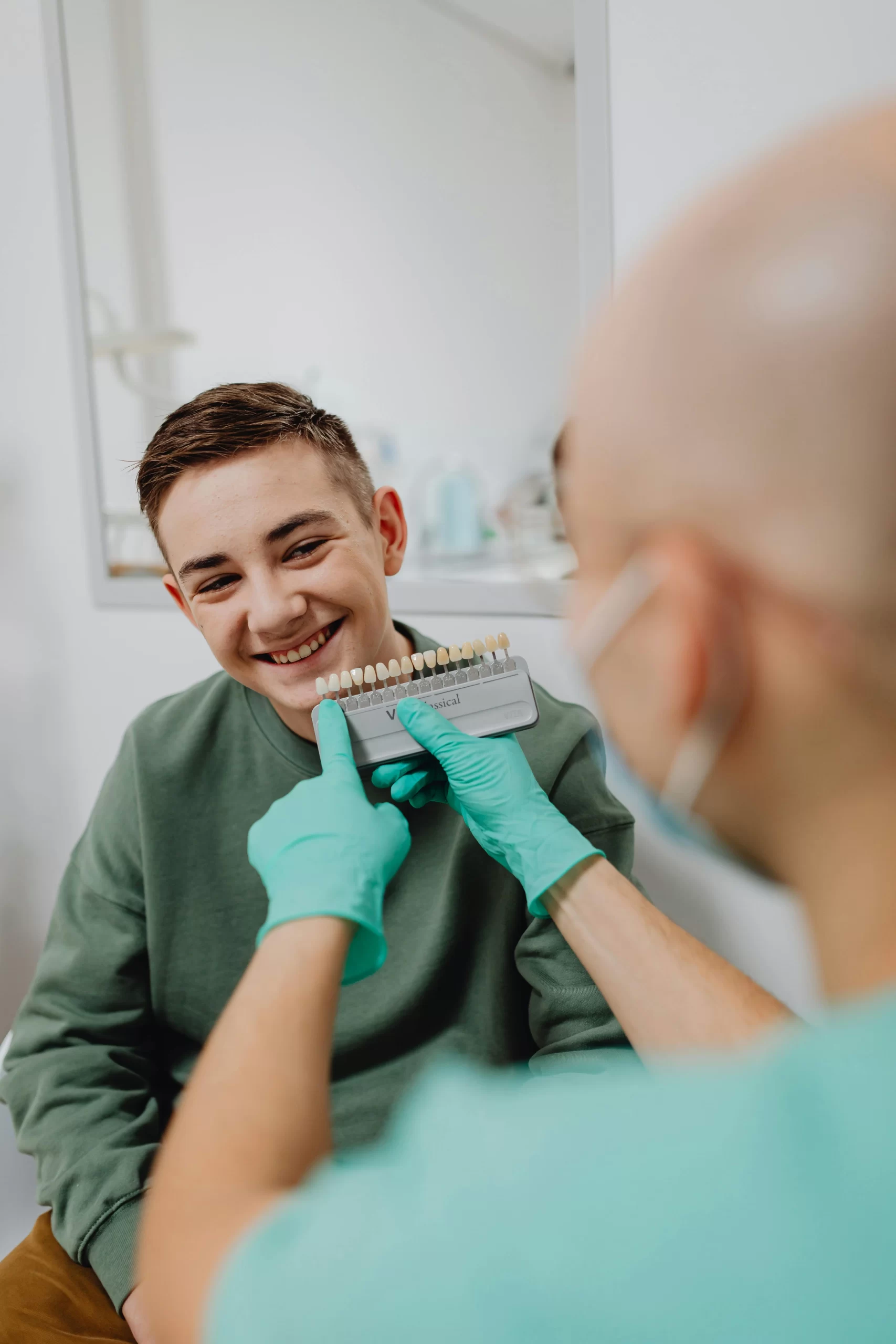 A boy smiling and a dentist holding a dental shade guide.